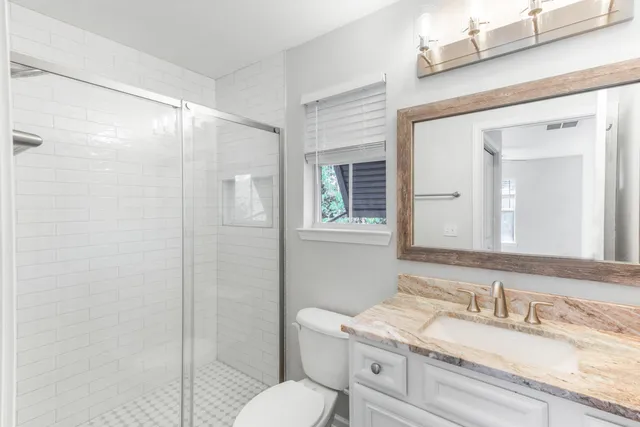 an empty room with wooden floor a ceiling fan and windows