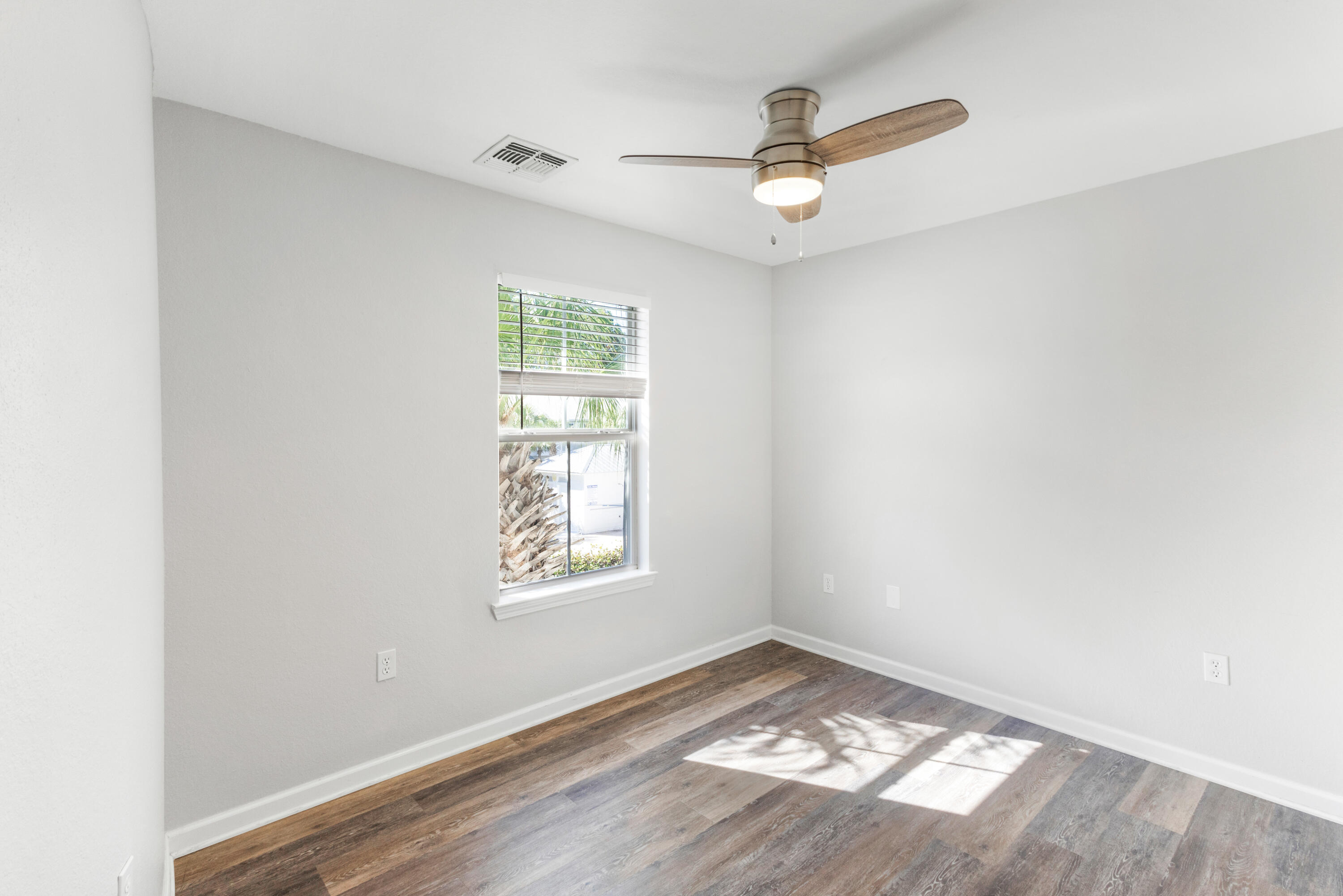 24 Talon Court, Unit C Santa Rosa Beach, FL 32459 - Photo 22 of 29 an empty room with wooden floor a ceiling fan and windows