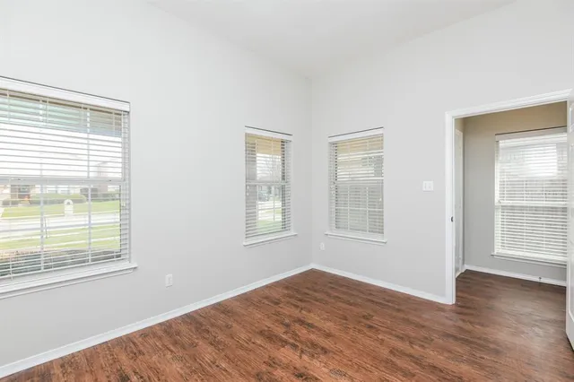 a view of an empty room with wooden floor and windows