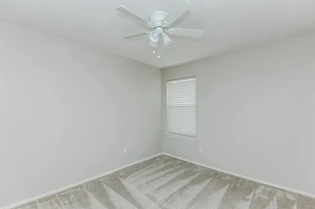 an empty room with a chandelier fan and windows