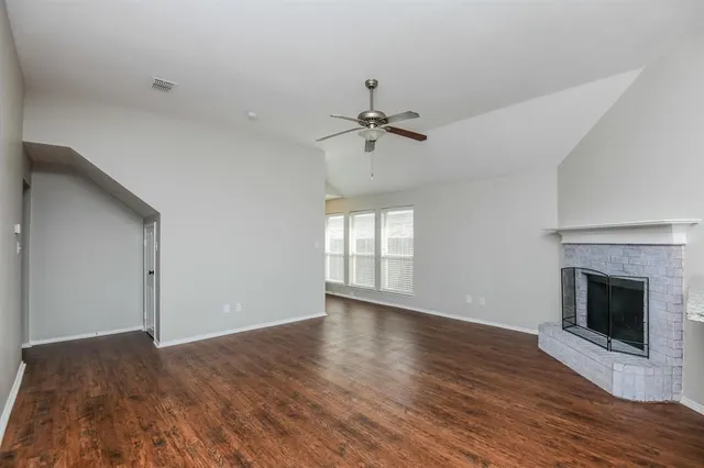 a view of an empty room with wooden floor fireplace and a window