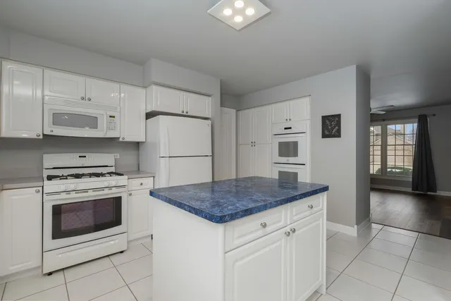 a kitchen with stainless steel appliances granite countertop a stove a refrigerator and a white cabinets