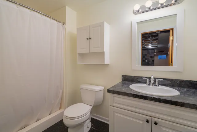 a bathroom with a granite countertop sink a toilet and a mirror
