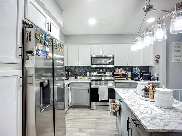 a kitchen with stainless steel appliances granite countertop a refrigerator a stove and a sink