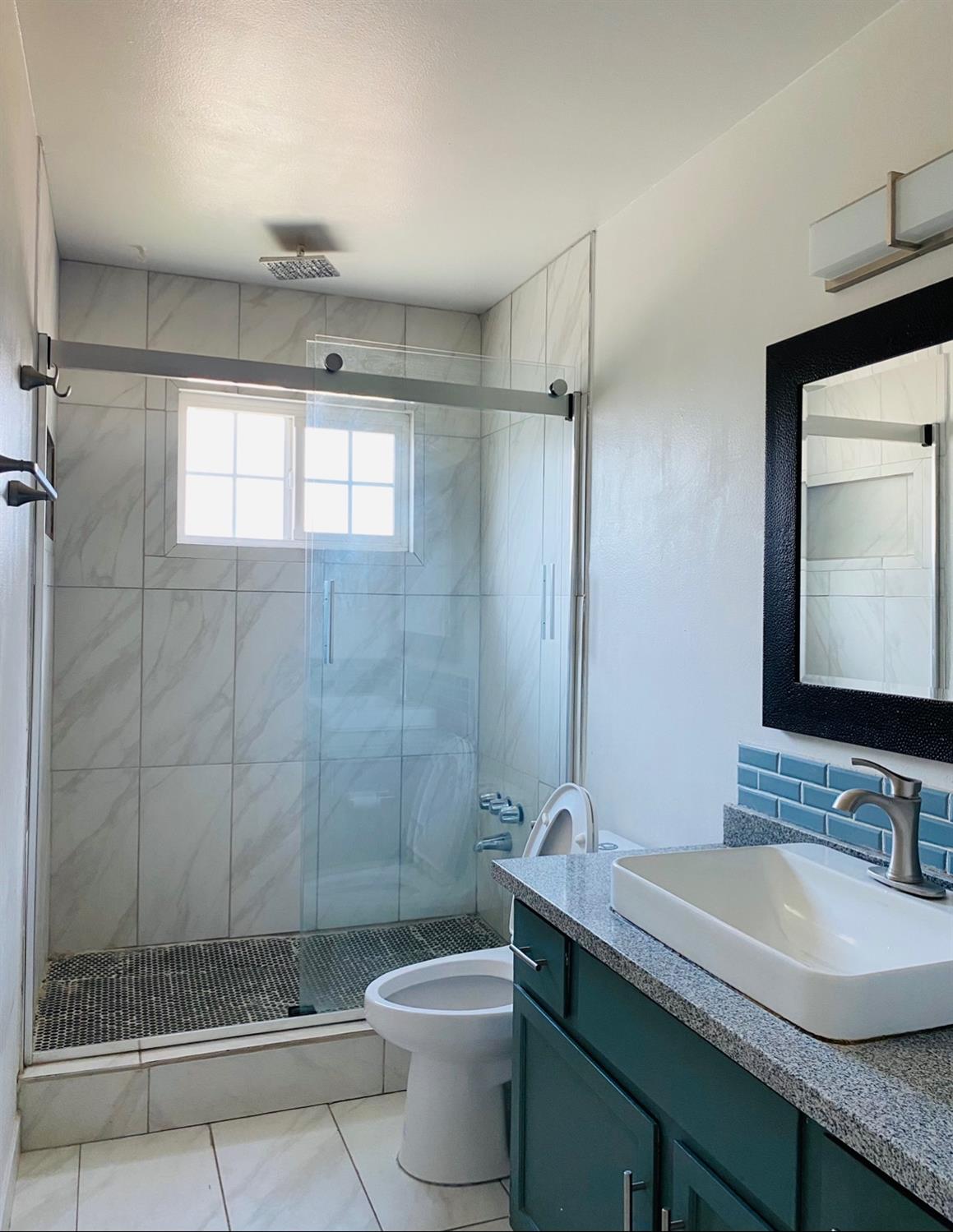 115 Gettysburg Avenue Clovis, CA 93612 - Photo 10 of 17 a bathroom with a granite countertop sink toilet a mirror and shower