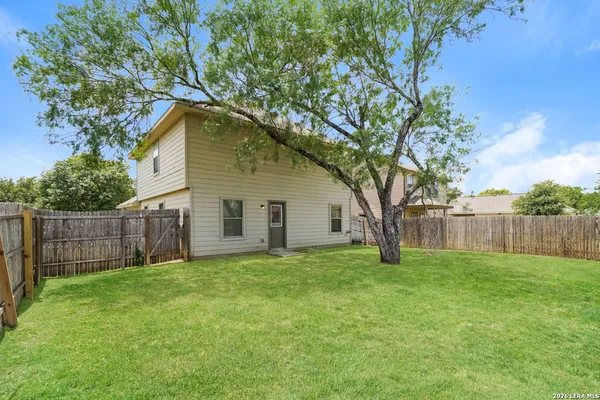 a view of a backyard with a tree and wooden fence