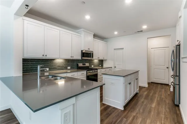 a kitchen with stainless steel appliances kitchen island granite countertop a stove a sink and a refrigerator