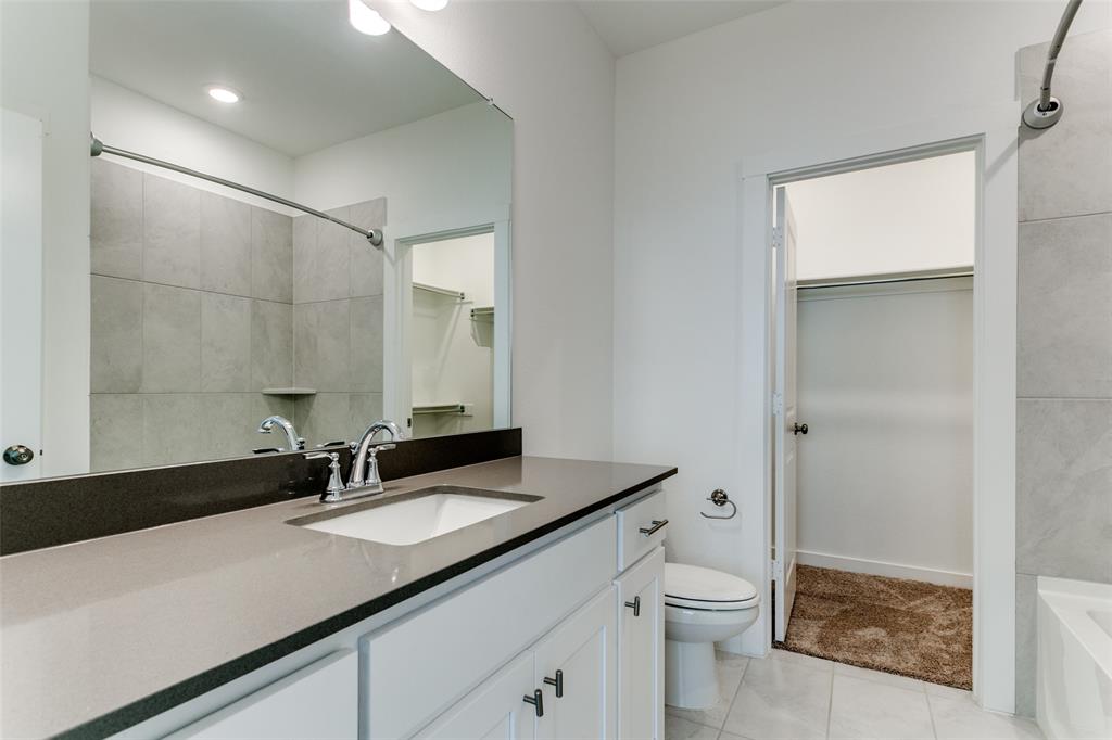 663 Vista Oaks Road Lewisville, TX 75067 - Photo 9 of 12 a bathroom with a granite countertop sink a toilet and a mirror
