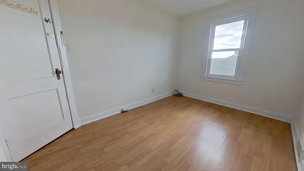 an empty room with wooden floor and window