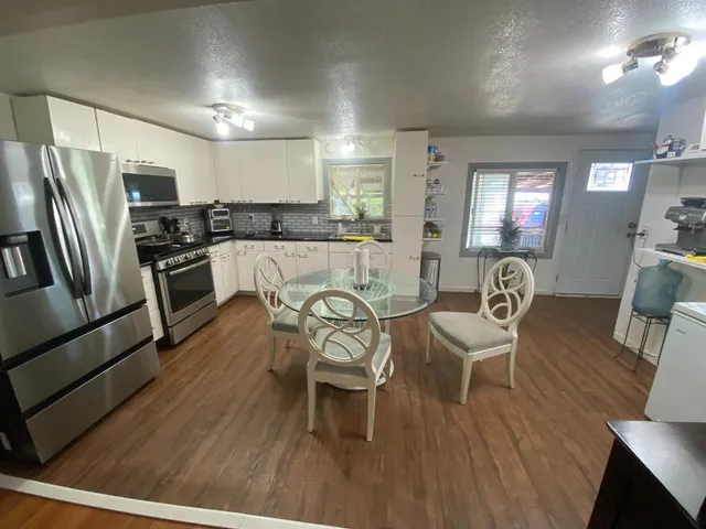 a kitchen with stainless steel appliances granite countertop a dining table chairs refrigerator sink and cabinets