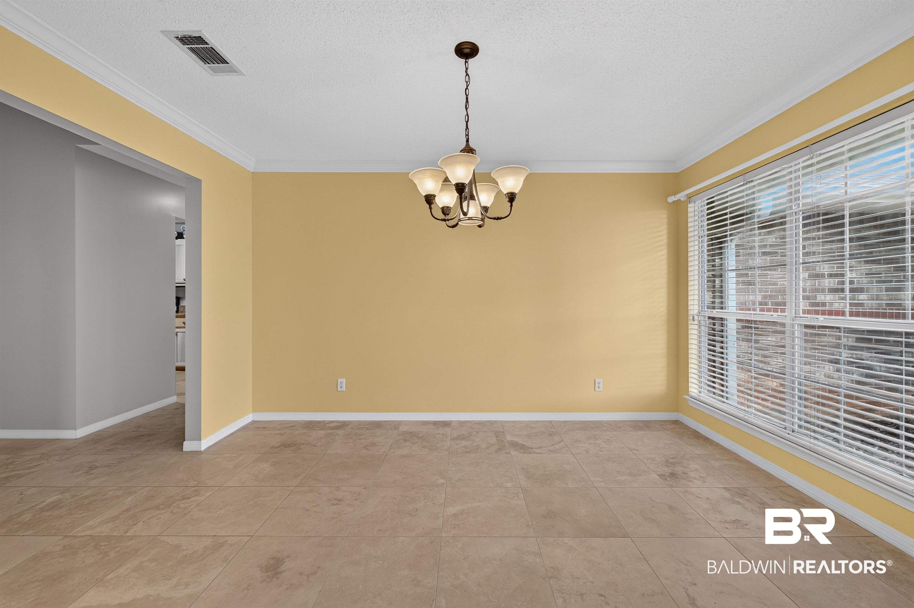 22685 County Road 12 Foley, AL 36535 - Photo 26 of 89 Expansive room featuring large window with blinds, tile flooring, a multi-bulb chandelier, crown molding, and an open doorway