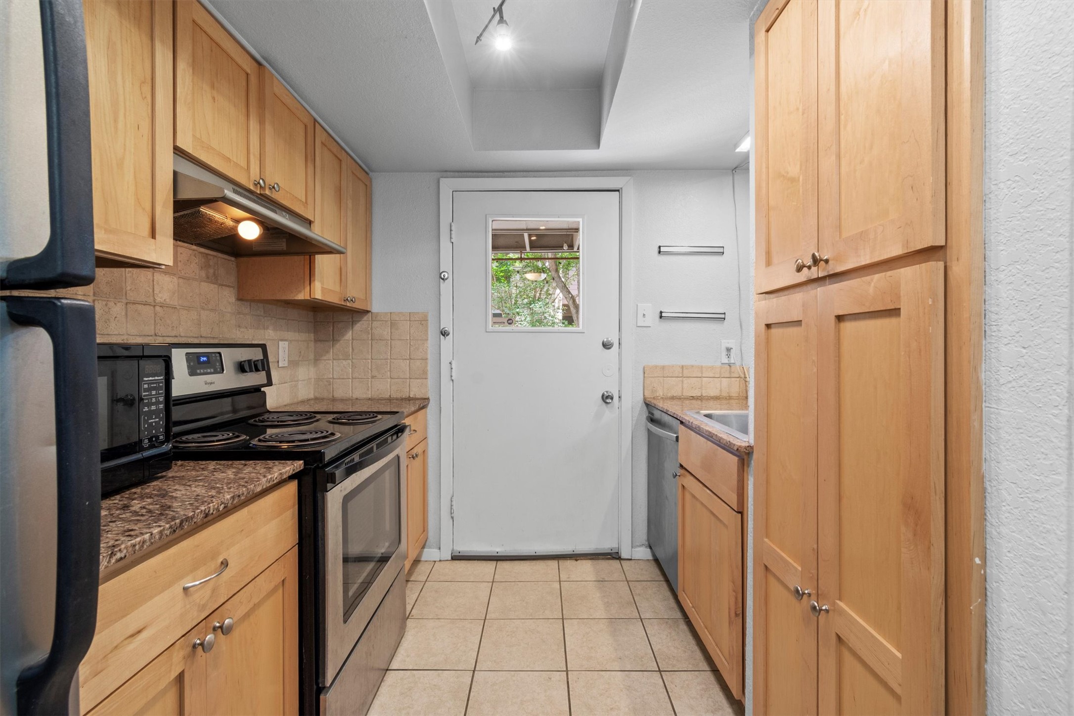 3627 Menchaca Road, Unit 204 Austin, TX 78704 - Photo 7 of 23 A galley kitchen with natural wood cabinetry and practical appliances offers efficient meal preparation.