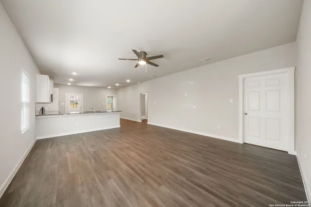 a view of an empty room with a kitchen and wooden floor
