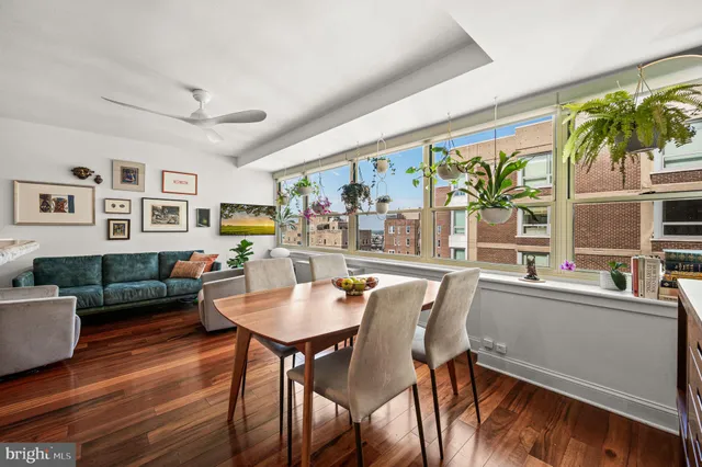 a dining room with furniture a floor to ceiling window and wooden floor