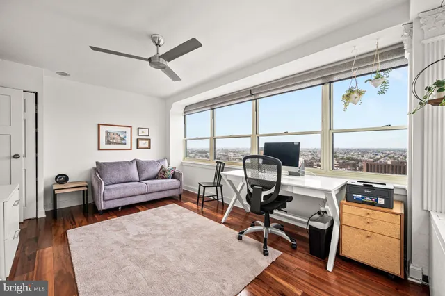 a living room with furniture a large window and wooden floor