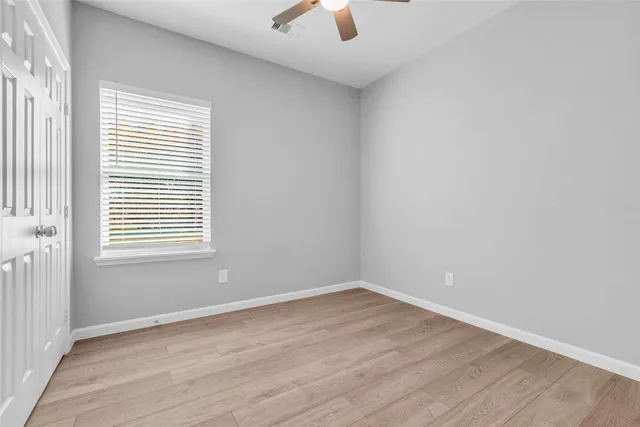 an empty room with a window and a ceiling fan