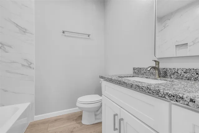 a bathroom with a granite countertop toilet and sink