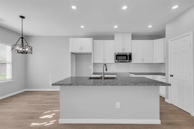 a kitchen with kitchen island granite countertop a sink a counter top space cabinets and stainless steel appliances