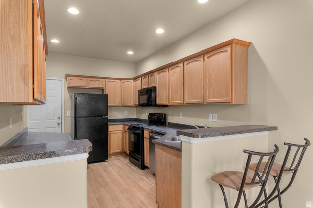 3053 Sage Loop, Unit B1 Lehi, UT 84043 - Photo 7 of 25 Spacious kitchen featuring wood cabinetry, dark countertops, full suite of black appliances, wood-finish flooring, and recessed lighting
