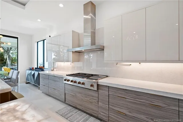 a large white kitchen with granite countertop lots of counter space and stainless steel appliances