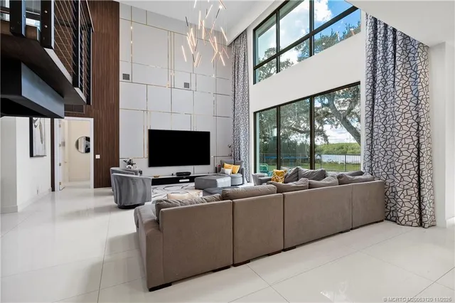 a living room with furniture a flat screen tv and a floor to ceiling window