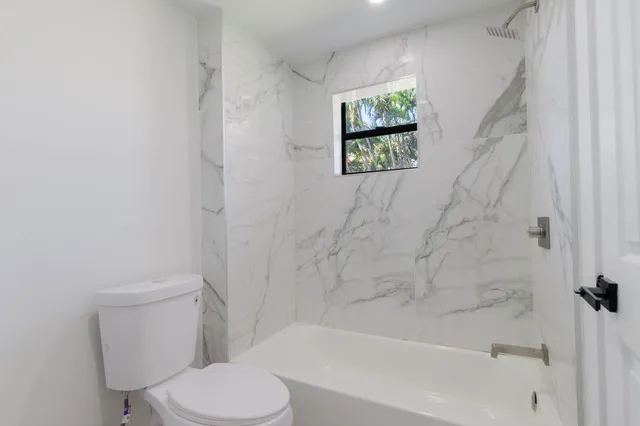 a white toilet sitting next to a bath tub