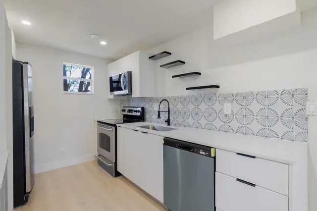 a kitchen with stainless steel appliances granite countertop white cabinets stove top oven and sink