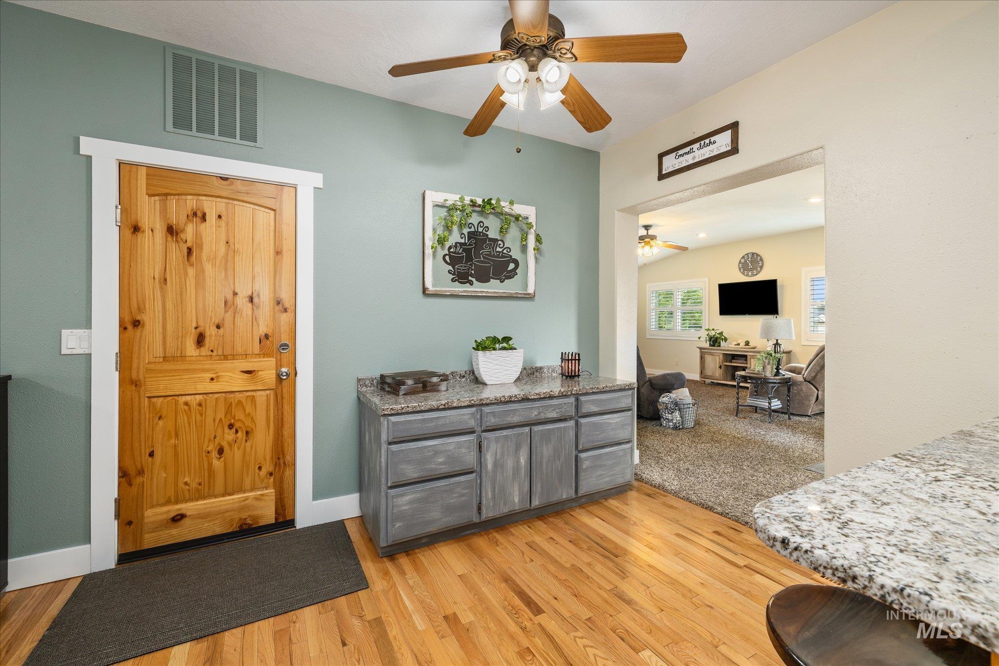 1140 Edgemont Road Emmett, ID 83617 - Photo 13 of 50 Interior space featuring a knotty pine door with white trim, wood-finish flooring, a ceiling fan with light fixture, and a built-in cabinet with a stone-look countertop
