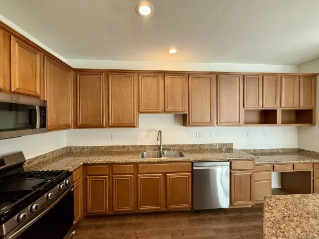 a kitchen with granite countertop a stove top oven sink and cabinets