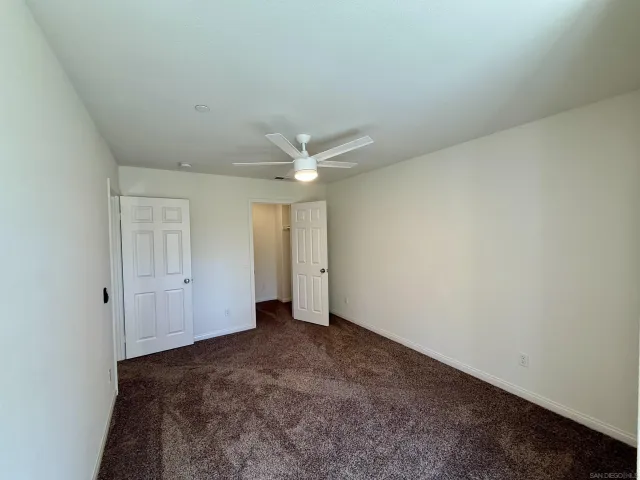 an empty room with a ceiling fan and closet area