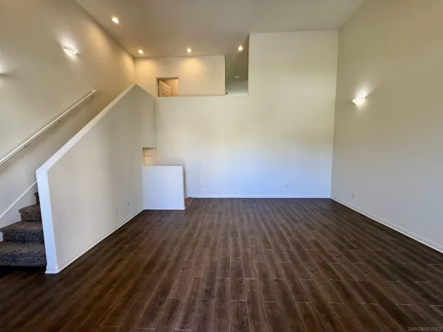 a view of an empty room with wooden floor and stairs