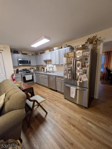 a kitchen with stainless steel appliances a stove a refrigerator and wooden floor