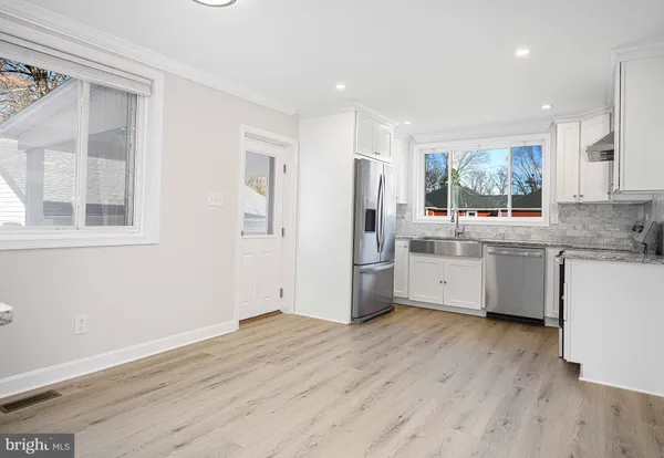a kitchen with stainless steel appliances a white cabinets and wooden floors