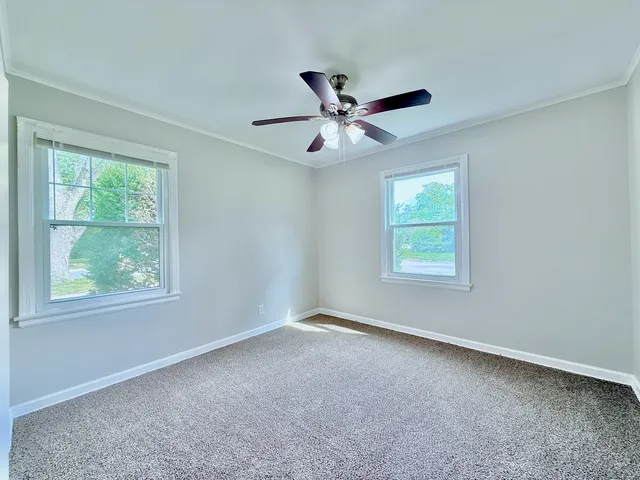 an empty room with a window and a fan