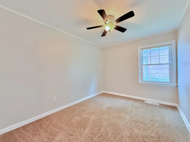 an empty room with a window and a fan