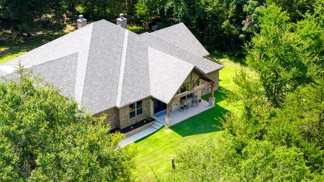 a aerial view of a house with swimming pool and large trees