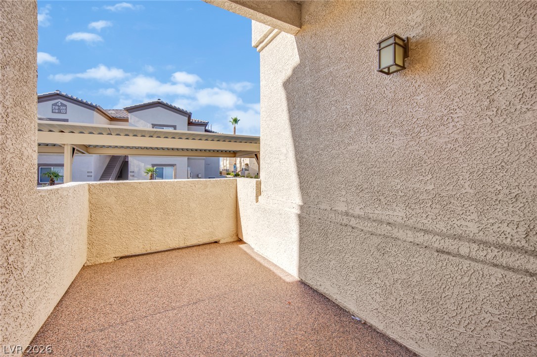 8725 West Flamingo Road, Unit 110 Las Vegas, NV 89147 - Photo 5 of 30 A private patio space with a textured stucco finish and an outdoor light fixture offers a secluded retreat.