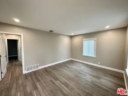a view of an empty room with wooden floor and closet