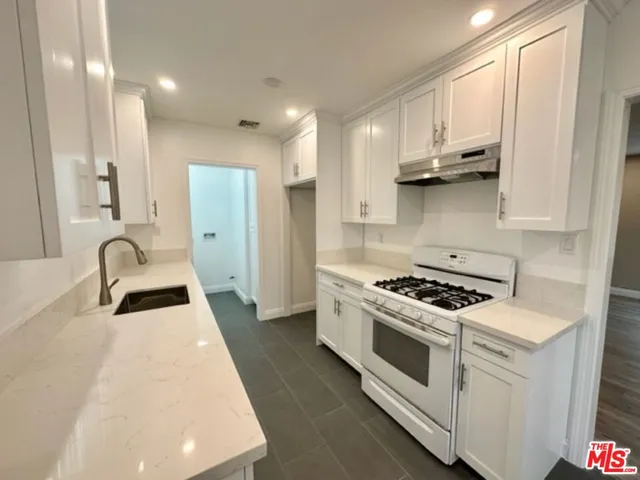 a kitchen with stainless steel appliances granite countertop a stove a sink and a refrigerator