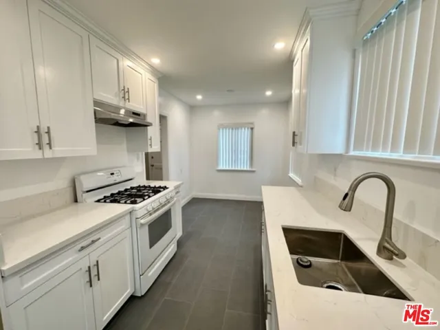 a kitchen with stainless steel appliances granite countertop a sink a stove and a refrigerator