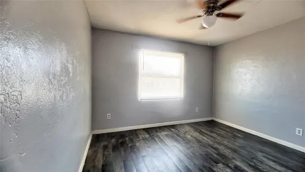 an empty room with a window and a fan