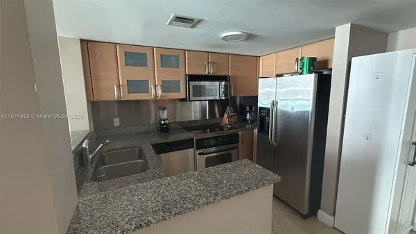 a kitchen with granite countertop a refrigerator and a sink