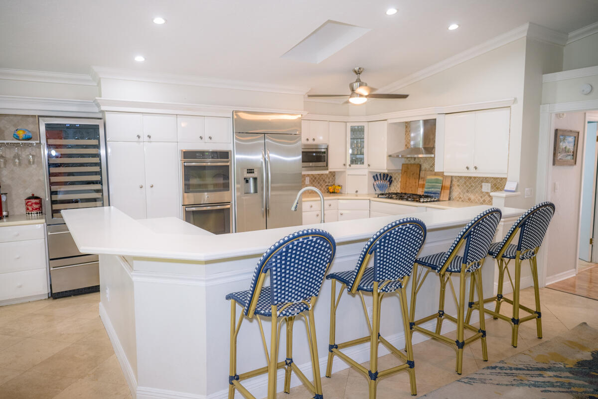 464 Lime Drive Key Largo, FL 33037 - Photo 56 of 96 a kitchen with stainless steel appliances kitchen island granite countertop a refrigerator a stove a microwave oven a dining table and chairs with wooden floor