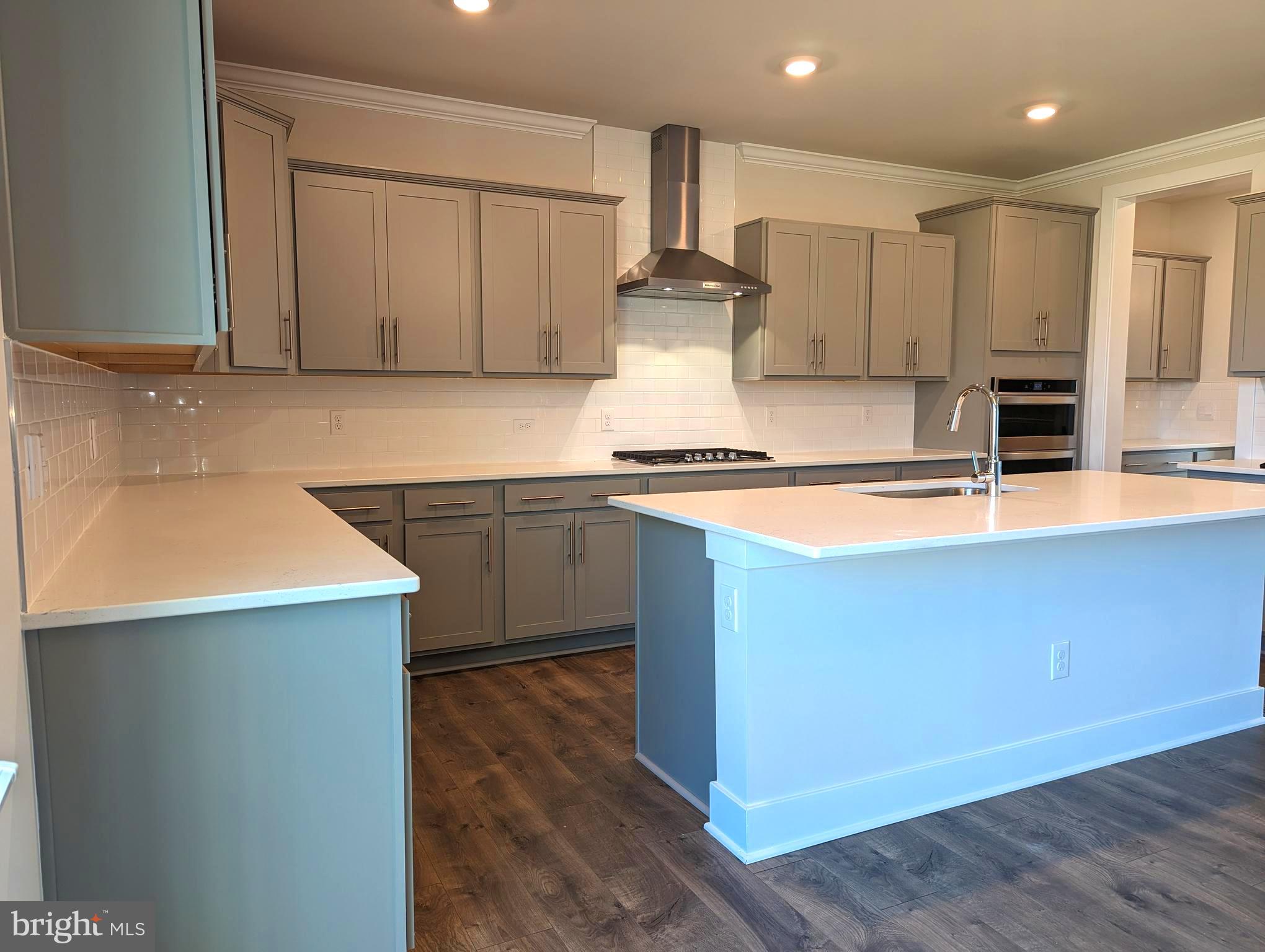14972 Walter Robinson Lane Haymarket, VA 20169 - Photo 16 of 30 a kitchen with kitchen island granite countertop a sink a stove and white cabinets