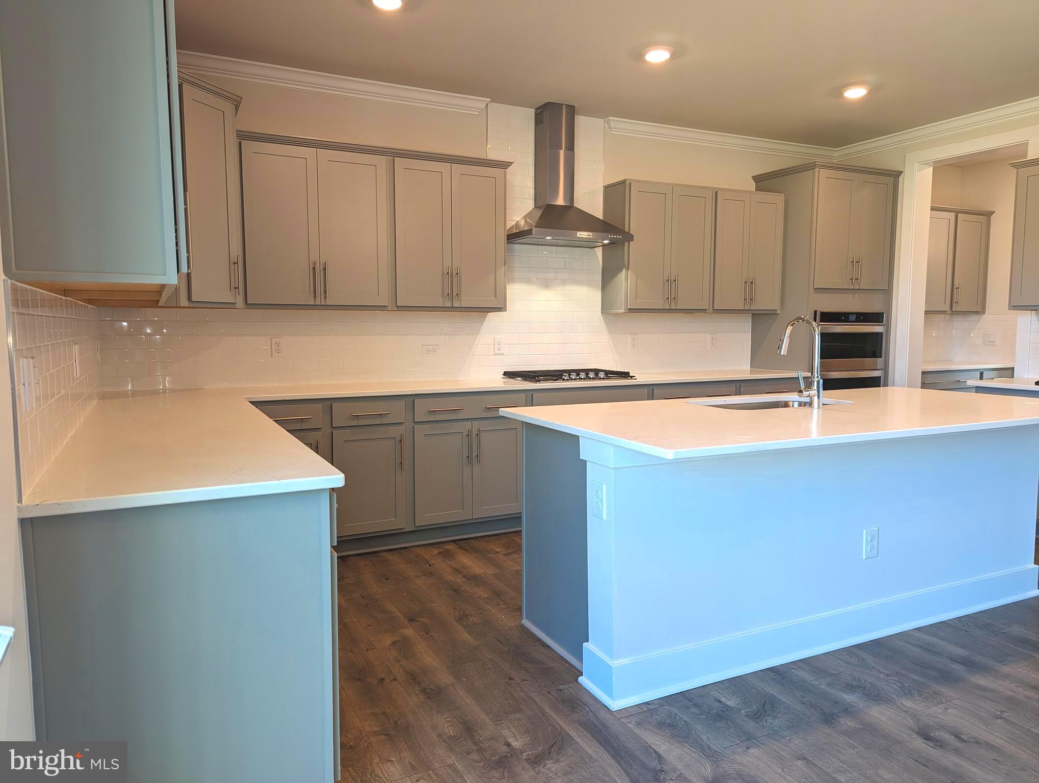 14972 Walter Robinson Lane Haymarket, VA 20169 - Photo 5 of 30 a kitchen with kitchen island granite countertop a sink a stove and white cabinets