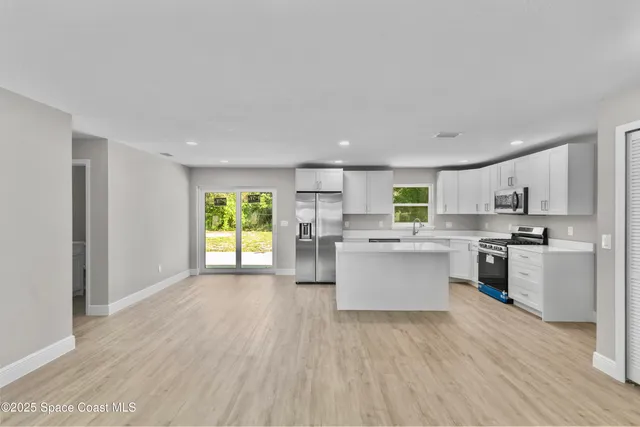 a kitchen with a refrigerator and white cabinets