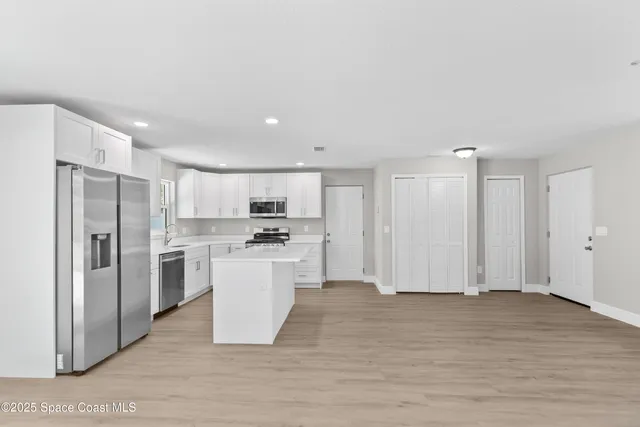 a kitchen with stainless steel appliances kitchen island a refrigerator sink and cabinets