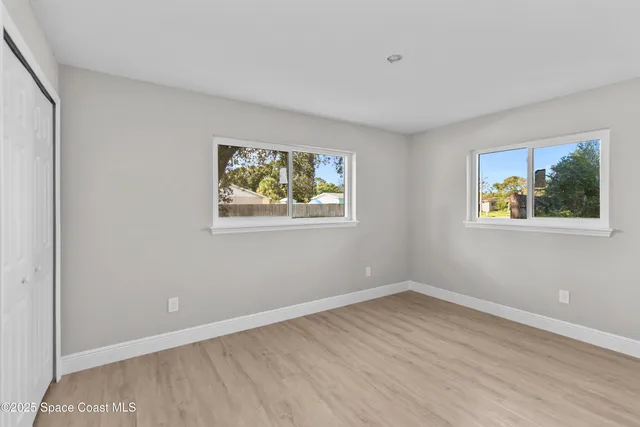 a view of an empty room with wooden floor and window