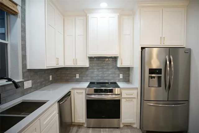 a large white kitchen with a sink and dishwasher a stove top oven with wooden floor