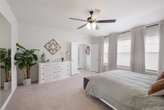 a bedroom with a bed chandelier dresser and a window
